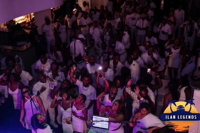 A packed room of guests in white